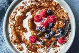 Oatmeal breakfast bowl topped with fresh raspberries, blueberries, and cinnamon swirl, served in a ceramic dish