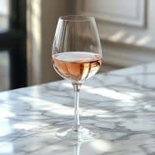 Glass of rosé wine on a marble table in a bright, minimalist dining setting