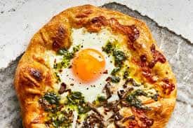 Flatbread pizza with baked egg, herbs, and melted cheese on a crispy crust
