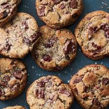 Homemade chocolate chip cookies with chunks of melted chocolate, baked to a golden brown on a baking tray