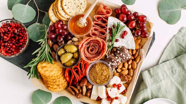 Artisan charcuterie board with cured meats, cheeses, olives, grapes, crackers, and honey, styled for entertaining