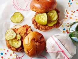 Crispy fried chicken sandwich with pickles on a soft bun, served in casual fast food style