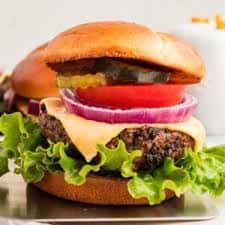 Juicy cheeseburger with lettuce, tomato, onion, and pickles on a toasted bun