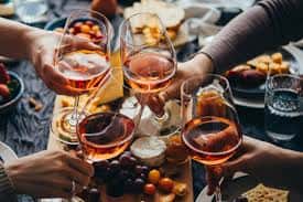 Friends toasting glasses of rosé wine over a charcuterie spread in a social dining setting