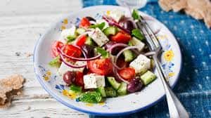 Fresh Greek salad with cucumber, tomatoes, olives, red onion, and feta cheese on a light plate