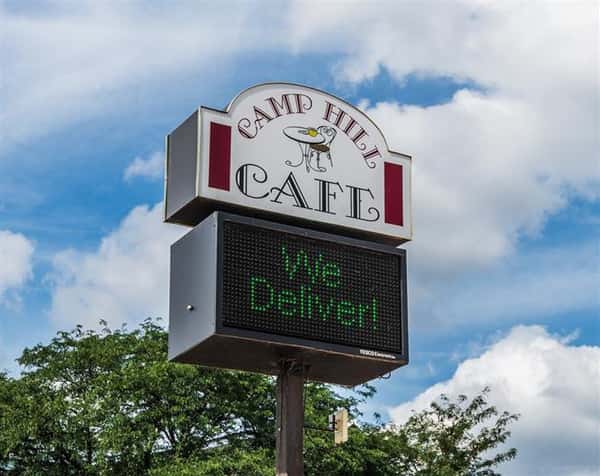Camp Hill Cafe road sign with electronic readerboard underneath stating "We Deliver"