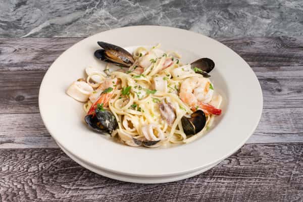 Seafood fettuccine Alfredo with shrimp, scallops, and mussels in creamy white sauce, garnished with parsley