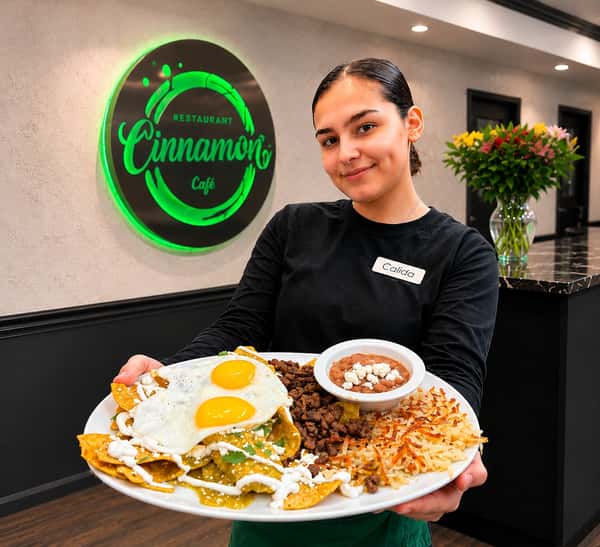 Server presenting a variety of breakfast favorites including eggs, pancakes, and traditional Salvadoran dishes at Cinnamon Restaurant Café.