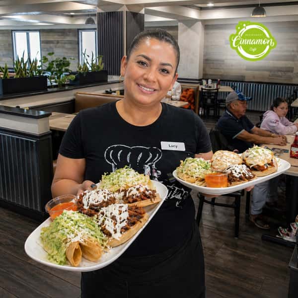 Friendly server carrying freshly prepared breakfast plates through the dining room at Cinnamon Restaurant Café.
