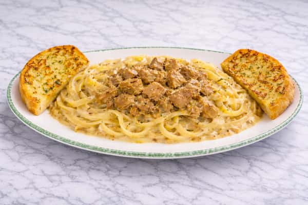 Creamy pasta topped with seasoned ground beef and grated cheese, served with toasted garlic bread at Cinnamon Restaurant Café.