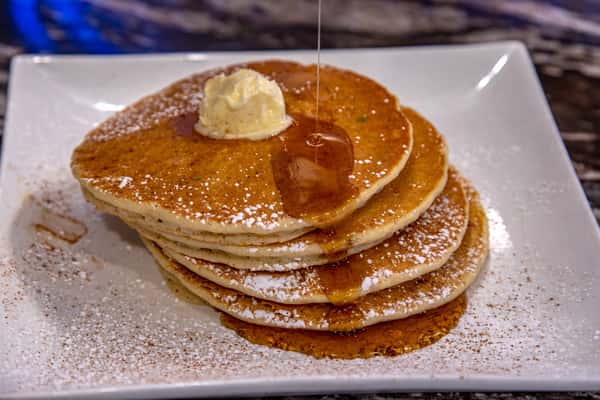 Stack of fluffy buttermilk pancakes topped with butter and syrup at Cinnamon Restaurant Café.