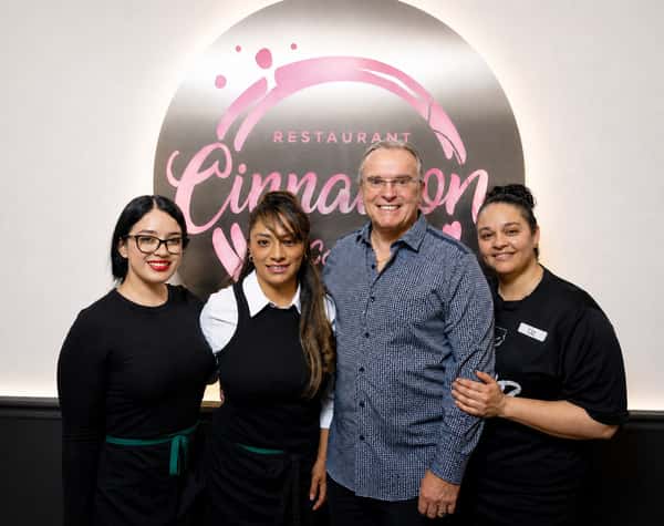 Cinnamon Restaurant Café team members smiling together in front of the restaurant logo, celebrating hospitality and teamwork.