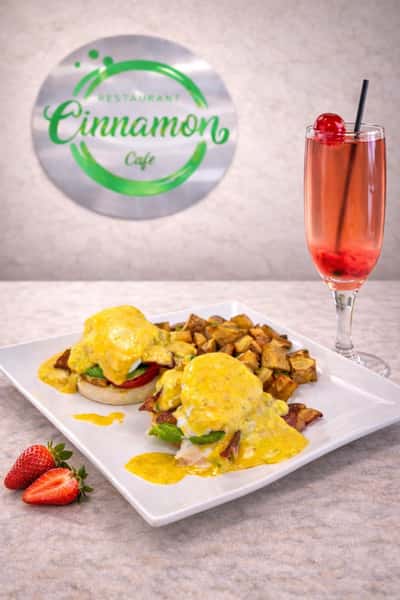 Eggs Benedict served with breakfast potatoes and a refreshing fruit beverage at Cinnamon Restaurant Café.