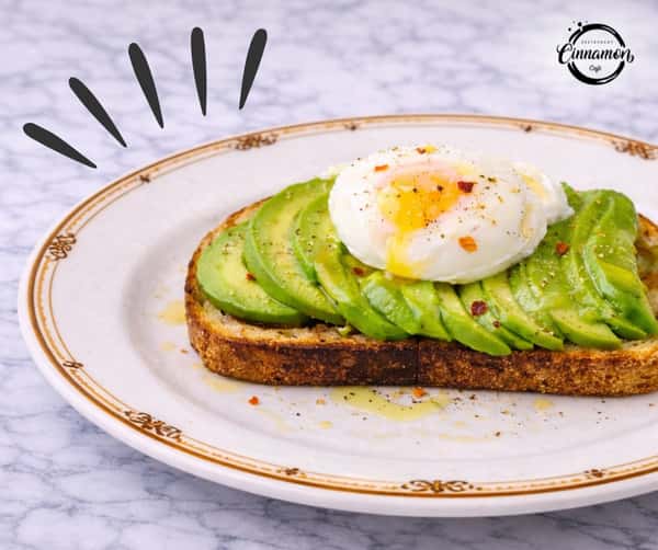 Avocado toast topped with a perfectly cooked egg and seasoning on artisan bread.