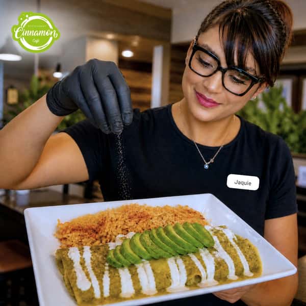 Team member presenting a colorful dessert topped with fresh fruit and sauce at Cinnamon Restaurant Café.
