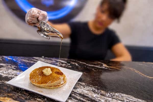 Fresh syrup being poured over a stack of golden pancakes at Cinnamon Restaurant Café.