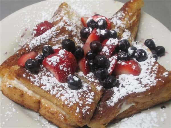 french toast topped with powdered sugar, strawberries and blueberries