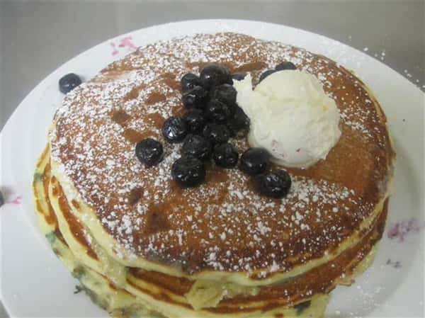 stack of panckes topped with blueberries and butter