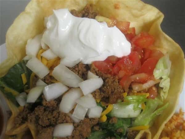 taco salad with onions, lettuce, tomatoes, cheese and sour cream
