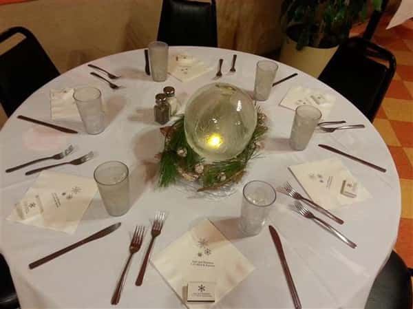 round table with napkins, glasses, silverware and lighted candle in the middle