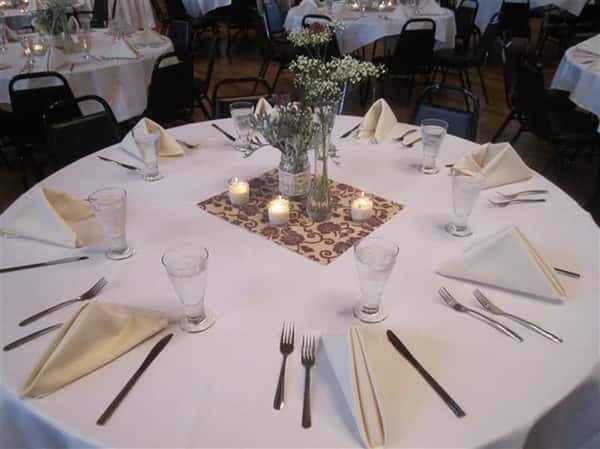 round table with napkins, silverware, glasses and center piece