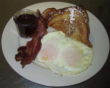 french toast, bacon, eggs, and blueberry topping on the side
