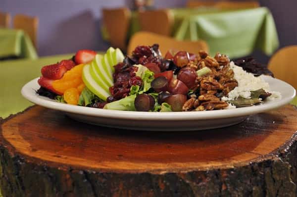 A fresh fruit salad topped with nuts and shredded cheese