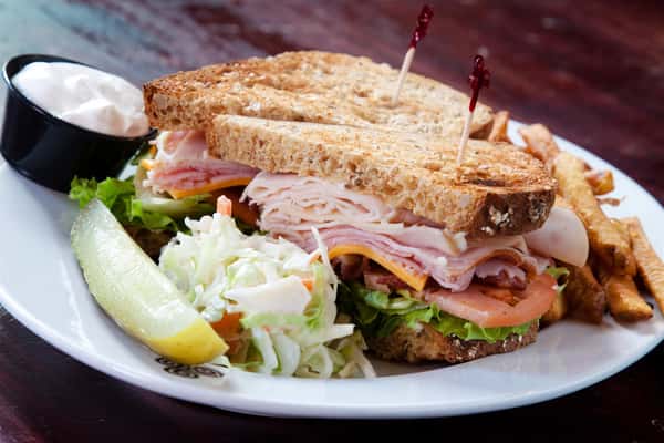 A club sandwich served with colesalw, side fries and a dipping sauce