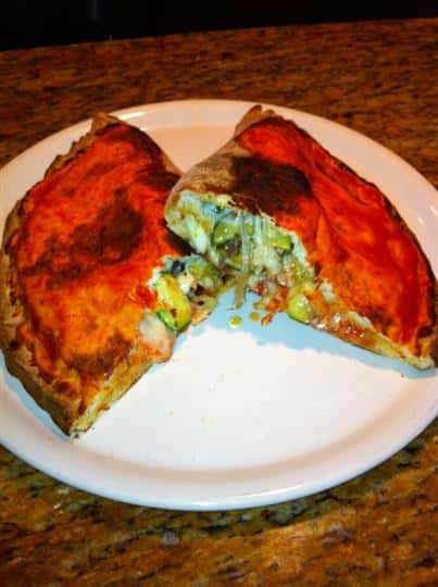 Vegetable calzone with melted cheese halved and served in white dish