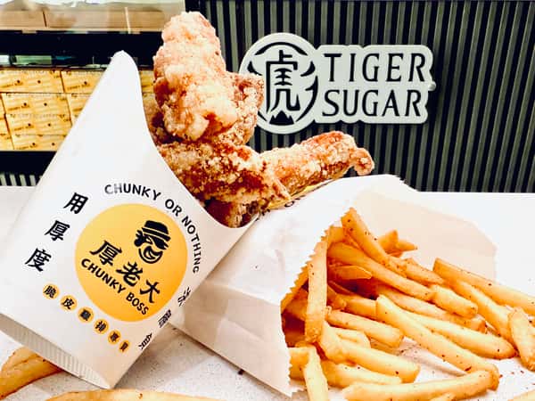 Crispy fried chicken and seasoned fries in branded Chunky Boss and Tiger Sugar packaging on a white counter.