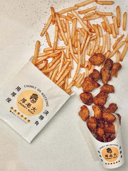 Crispy chicken bites and seasoned fries served with Chunky Boss branded packaging on a white countertop.