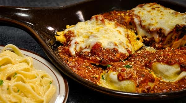 Baked ravioli in tomato sauce with melted cheese, served with a side of fettuccine alfredo.