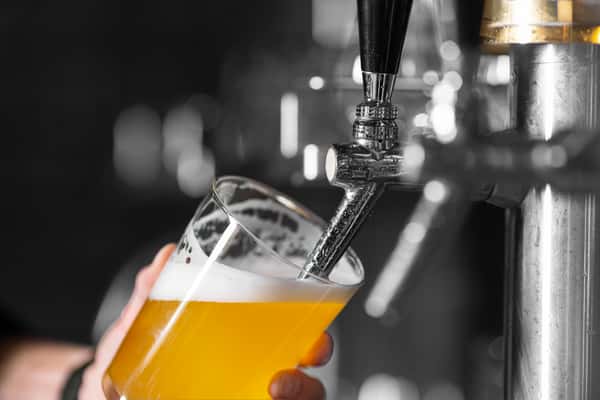 Fresh draft beer being poured from a tap into a pint glass at a modern craft brewery