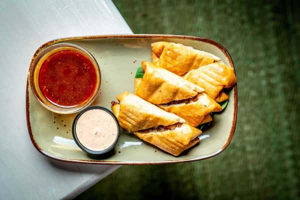 Grilled panini sandwiches cut into triangles, served with dipping sauces on a rustic plate, highlighting crispy texture and casual café-style dining.