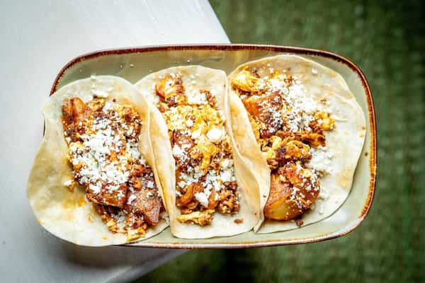 Street-style tacos filled with seasoned meat, potatoes, and crumbled cheese on soft tortillas, showcasing authentic Mexican flavors.