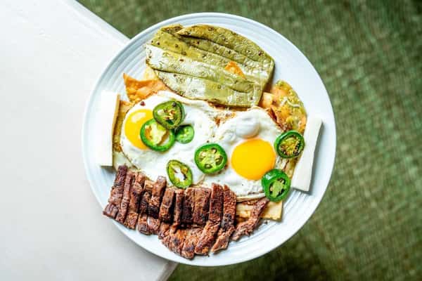 Savory steak and eggs breakfast plate with sliced grilled steak, sunny-side eggs, roasted vegetables, and fresh jalapeños for a bold, hearty dish.