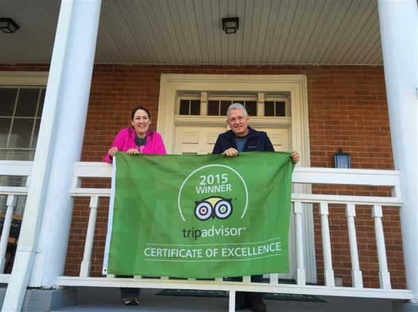 Kaye and Alan on balcony holding trip advisor 2015 winner of certificate of excellence banner.