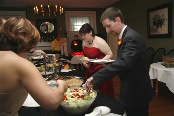 People serving themselves food at catering table