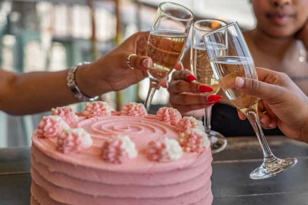 action shot of toasting behind a pink cake