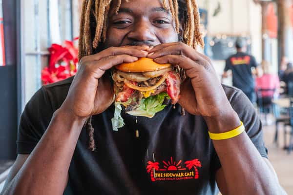 A Man Eating a John Irving Burger at The Sidewalk Cafe