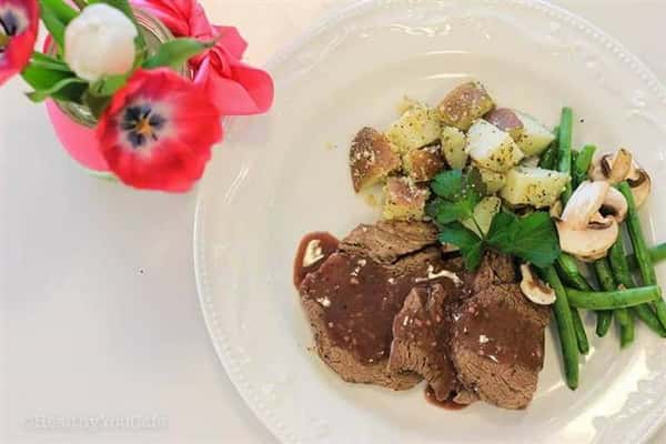 A plate of meatloaf topped with gravy, paired with potatoes, asparagus and mushrooms.