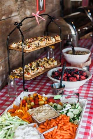 A close up of a food bar with mixed veggies, toast with brushetta topping and a berry salad.