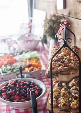 A food bar with a variety of different food, such as a berry salad and toast with brushetta topping.