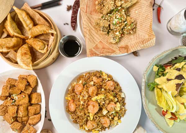 A vibrant spread from Pepper Salt in Houston, TX, featuring a central bowl of shrimp fried rice topped with scrambled eggs and green onions.