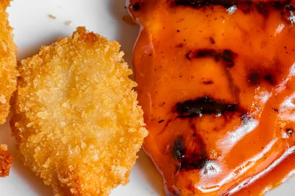 Close-up of breaded shrimp beside chargrilled chicken.