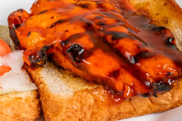 Close-up of chargrilled chicken on toast with lettuce and tomato.