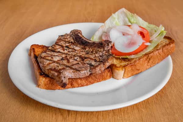 Grilled steak on toast with lettuce, tomato and onion, served open-faced.