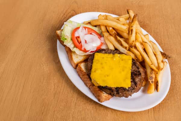 Cheeseburger on toast with french fries, lettuce, tomato and onion on a white plate.