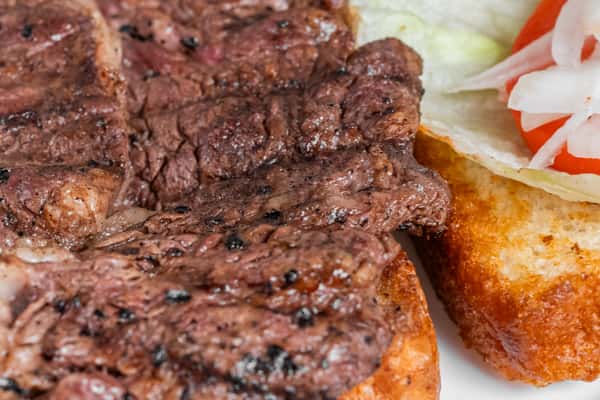 Close-up of chargrilled steak served on toasted bread.