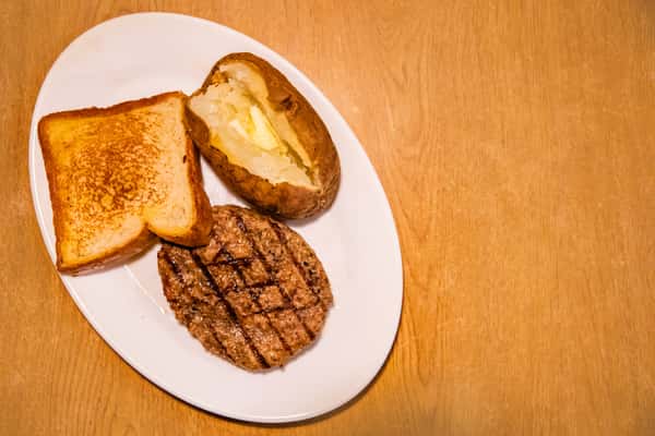 Grilled chopped steak with toast and a baked potato, viewed from above.